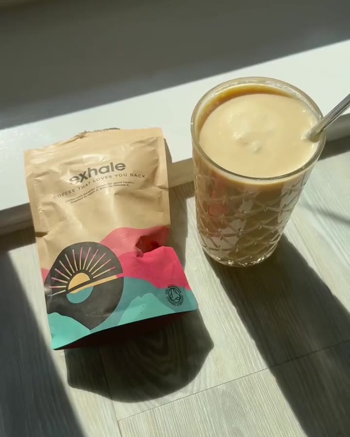 Coffee pouch beside a finished iced coffee in hard afternoon light